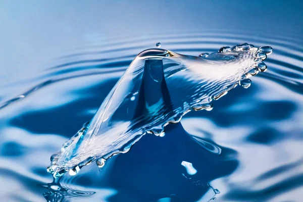 Two water drops colliding on blue water with ripples — Stock Photo, Image