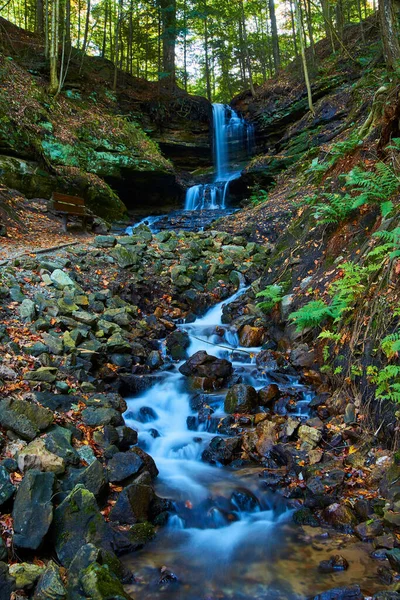 Hufeisenfall-Wasserfall mit kleinem Bach aus sichtbaren großen Felsen, der zu einer Klippe mit Baumwurzeln eines ausgesetzten Waldes führt — Stockfoto