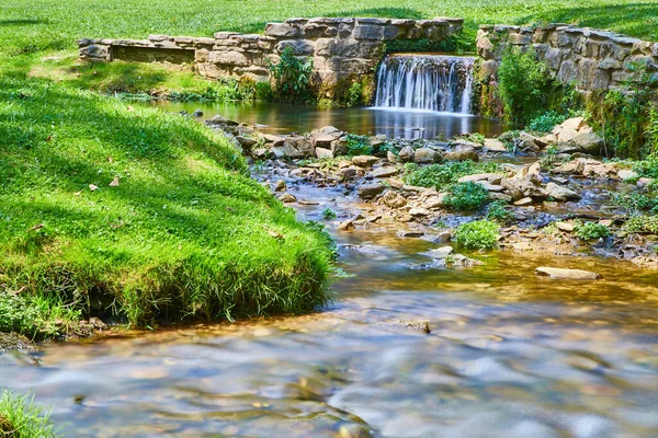 Cachoeira tranquila e pequena com paredes de pedra em um rio raso ou riacho — Fotografia de Stock