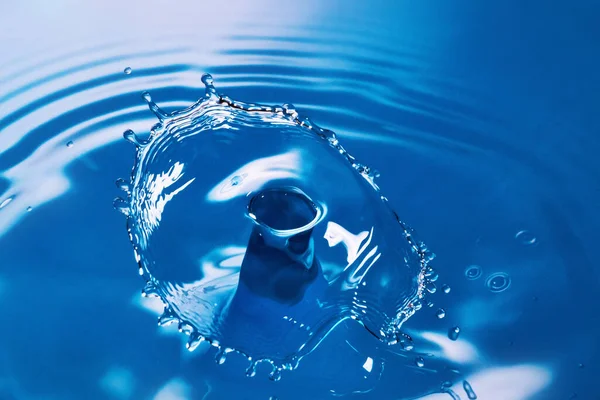 Дві краплі води розбиваються і створюють хвилі на блакитній воді — стокове фото