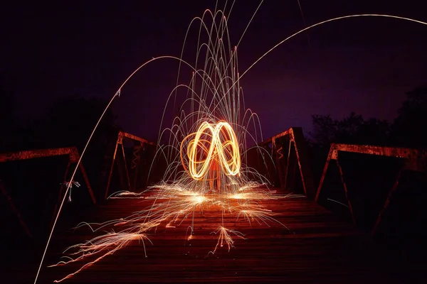 黄色の光の無限のシンボルと人との橋の上に夜に火花。 — ストック写真