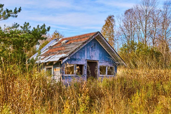 Старая хижина разваливается в поле с голубыми панелями — стоковое фото