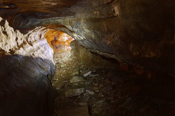 Cave with sunlight illuminating the exit at the far end — Stock Photo, Image