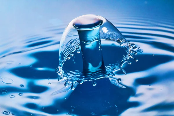Collision of two water drops on blue water with ripples — Stock Photo, Image