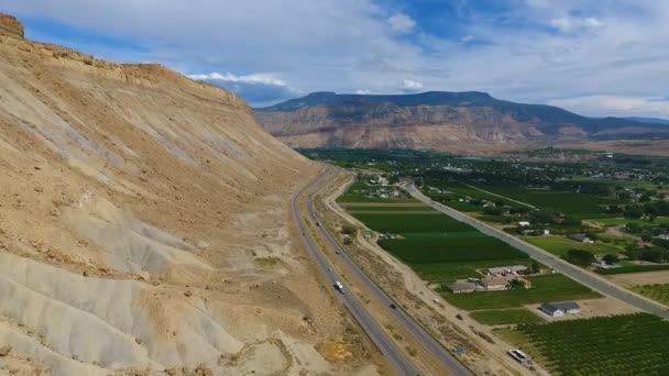 Aérea contra montañas de arena y carretera junto a granjas de melocotones Palisade en Colorado — Vídeo de stock