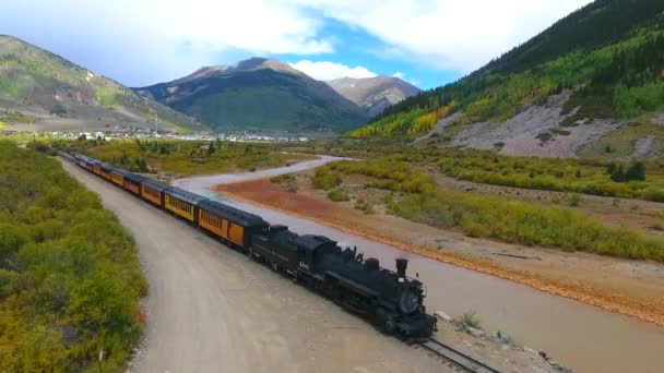 Aerial of locomotive train in mountain valley by stream leaving Silverton to Durango in Colorado — Stok Video