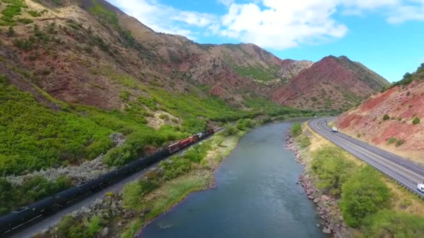 Zug auf Gleisen neben Colorado River in Schlucht roter Berge — Stockvideo