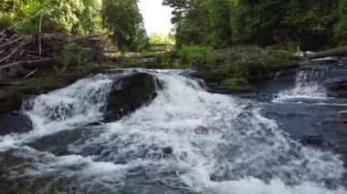 Uzakta demiryolu köprüsü olan çağlayan şelaleler boyunca alçak uçuş.