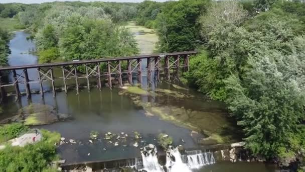 Antenne über Damm mit Wasserfällen neben alter Eisenbahnbrücke über gespaltenen Fluss — Stockvideo
