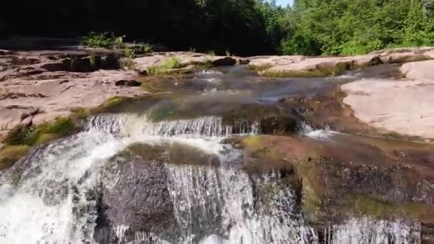 Ar para trás sobre o rio com rochas castanhas que levam à cascata serena — Vídeo de Stock
