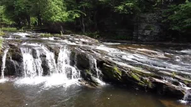 Aerial pan längs vattenfall över sloppade stenar — Stockvideo