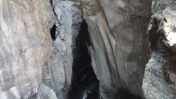 Luchtfoto naar beneden in diepe canyon met waterval die uit grot stroomt — Stockvideo
