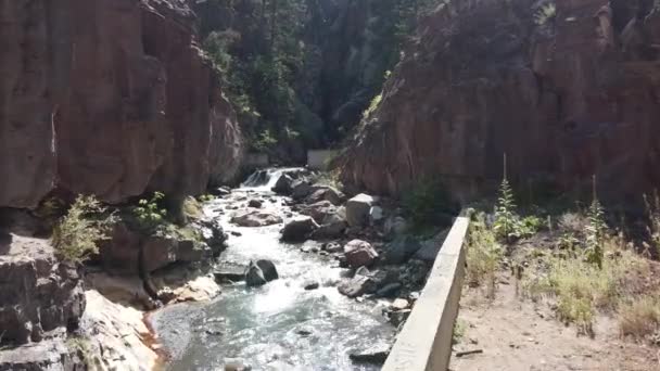 Aerea attraverso la base del canyon con muro di cemento e piccola cascata — Video Stock