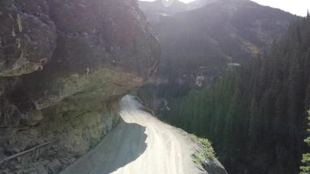 Aerial looking over edge from extremely dangerous and narrow gravel road on edge of cliffs in mountains — Stock Video