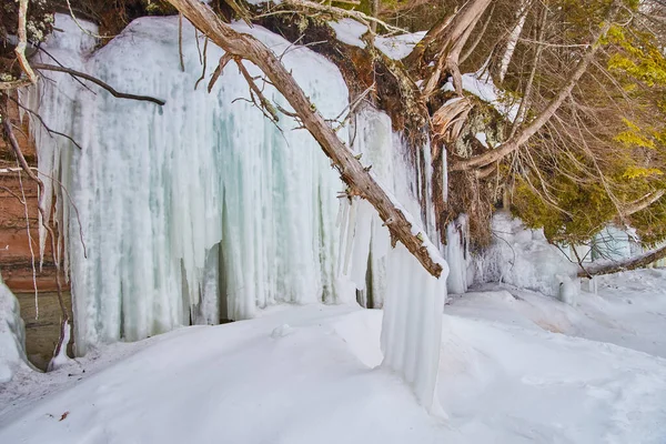 Klippen, die mit Eiskristallen bedeckt sind, mit Schwerpunkt auf Zweigen, die von großen Eiszapfen bedeckt sind — Stockfoto