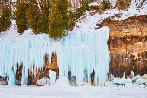 Rocky cliff detail in winter covered in blue ice and icicle formations — Stock Photo, Image