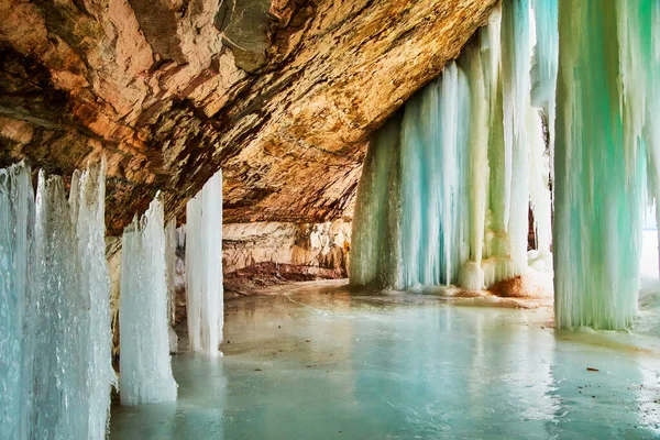 冰封的湖面和洞口充满了巨大的冰柱 — 图库照片