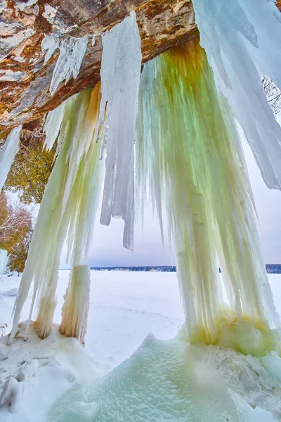 Zimą zamarznięte jezioro z jaskiniami i wiszącymi zielonymi soplami — Zdjęcie stockowe