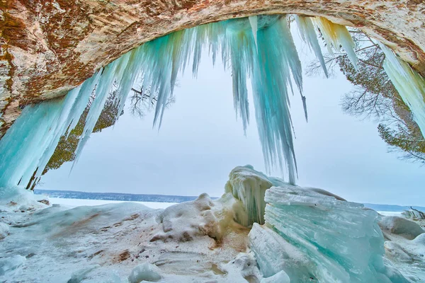 Buz mağarasının girişinde asılı mavi buz saçakları olan büyük buz parçaları. — Stok fotoğraf