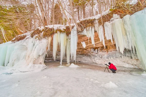 Valokuvaaja kuvaa jääpuikoista, jotka peittävät kallioita järvellä — kuvapankkivalokuva