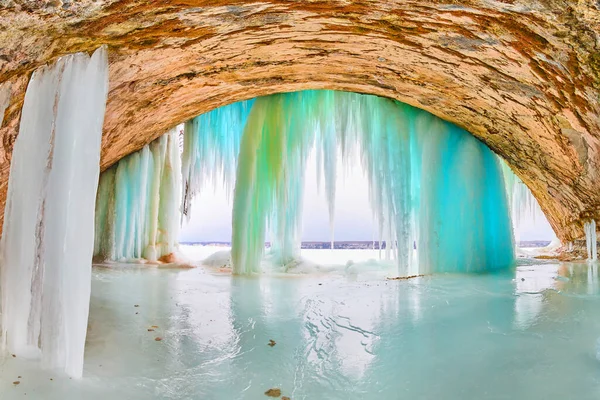 Entrada a la cueva de hielo con carámbanos altos azules y verdes y suelo cubierto de hielo — Foto de Stock