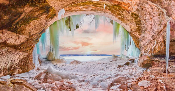 Piękna jaskinia lodowa podczas wschodu słońca zimą z dużymi niebieskimi i zielonymi soplami — Zdjęcie stockowe