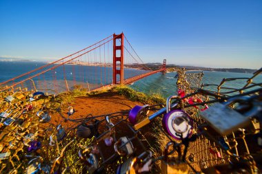 Gün batımında, çitlerin önü yüzlerce kilitle kaplı Golden Gate Köprüsü 'nün görüntüsü