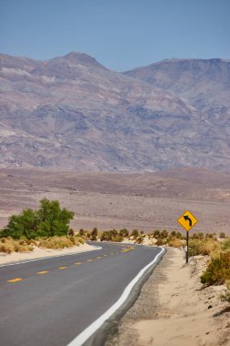 Çöldeki Paved Yolu 'nun resmi keskin virajlara ve dağlara götürüyor.