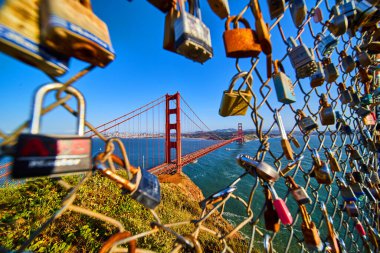 San Francisco 'nun ikonik Golden Gate Köprüsü' nün görüntüsü kilitlerle kaplı çitlerin içinden geçiyor.