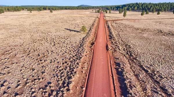 Image of Red dirt road straight through desert plains from aerial view