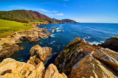 Bahar çiçekleriyle kaplı okyanus ve kayalıkların görüntüsü