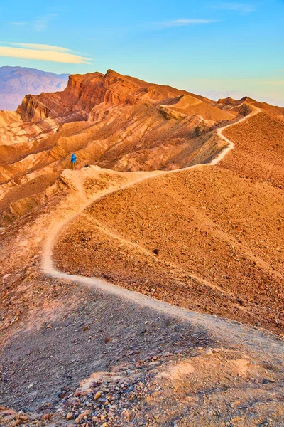 Image of Narrow hiking trail follows tip ridge of red sandy mountain in desert