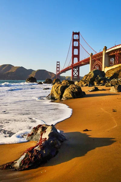 Image of Waves on stunning beaches next to Golden Gate Bridge with golden light from sunset