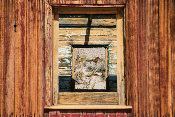 Image of View through abandoned ghost town train with window showing desert structure