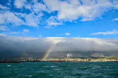 Güçlü rüzgar ve bulutlar dağlardan düşüyor. Novorossiysk 'te, limanın üzerinde bir gökkuşağı