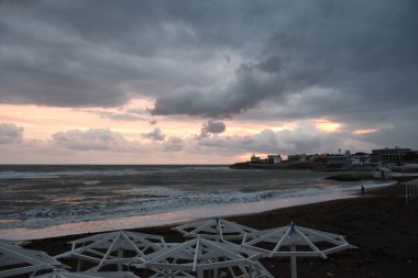 Akşamları, gün batımında pembe bulutların altında denizde bir fırtına olur. Gün batımında sahil boyunca bir yürüyüş.