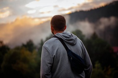 Dağlarda bir adam sisli bir günbatımı ormanının arka planında