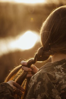 girl braiding a braid at sunset