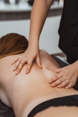 Masaj terapisti masaj salonundaki kadına masaj yapıyor.