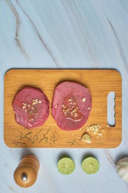 Tahta kesme tahtasında mermer masada taze çiğ ton balığı bifteği. Üst görünüm.