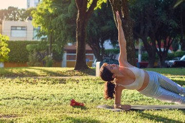 Latin genç kadın parkta yoga yapıyor.