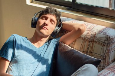 Genç adam evde müzik dinleyerek rahatlıyor. Ruh sağlığı kavramı, konfor bölgesi.