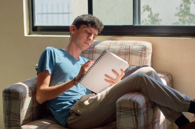 Genç adam evde yazarak rahatlıyor. Ruh sağlığı kavramı, konfor bölgesi.