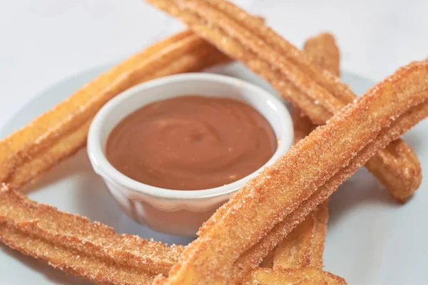 Şekerli ve tarçınlı geleneksel churro bir kase karamel ile mermer bir masada servis edilir..