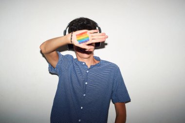 Gökkuşağı bayraklı neşeli gay adam müzik dinliyor..