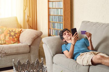 Genç Latin adam dijital kredi kartı kullanarak online alışveriş yapıyor..