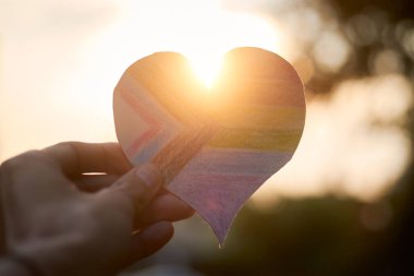 Yeni LGBT gurur bayrağı kalp şeklinde, arkasında güneş ışığı var..