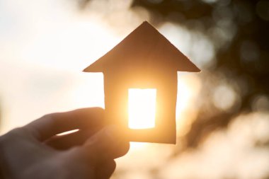 Yenilenebilir kaynaklara sahip inşaat konsepti, arkasında güneş ışığı olan karton ev..