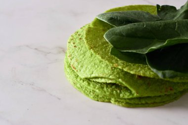 Ispanaklı yeşil tortilla, dürümler için yuvarlak boş tortilla, modaya uygun Meksika yemekleri, sağlıklı atıştırmalık konsepti