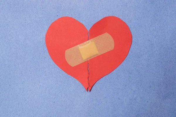 Abstract concept of love. Broken paper heart with medical health patch.